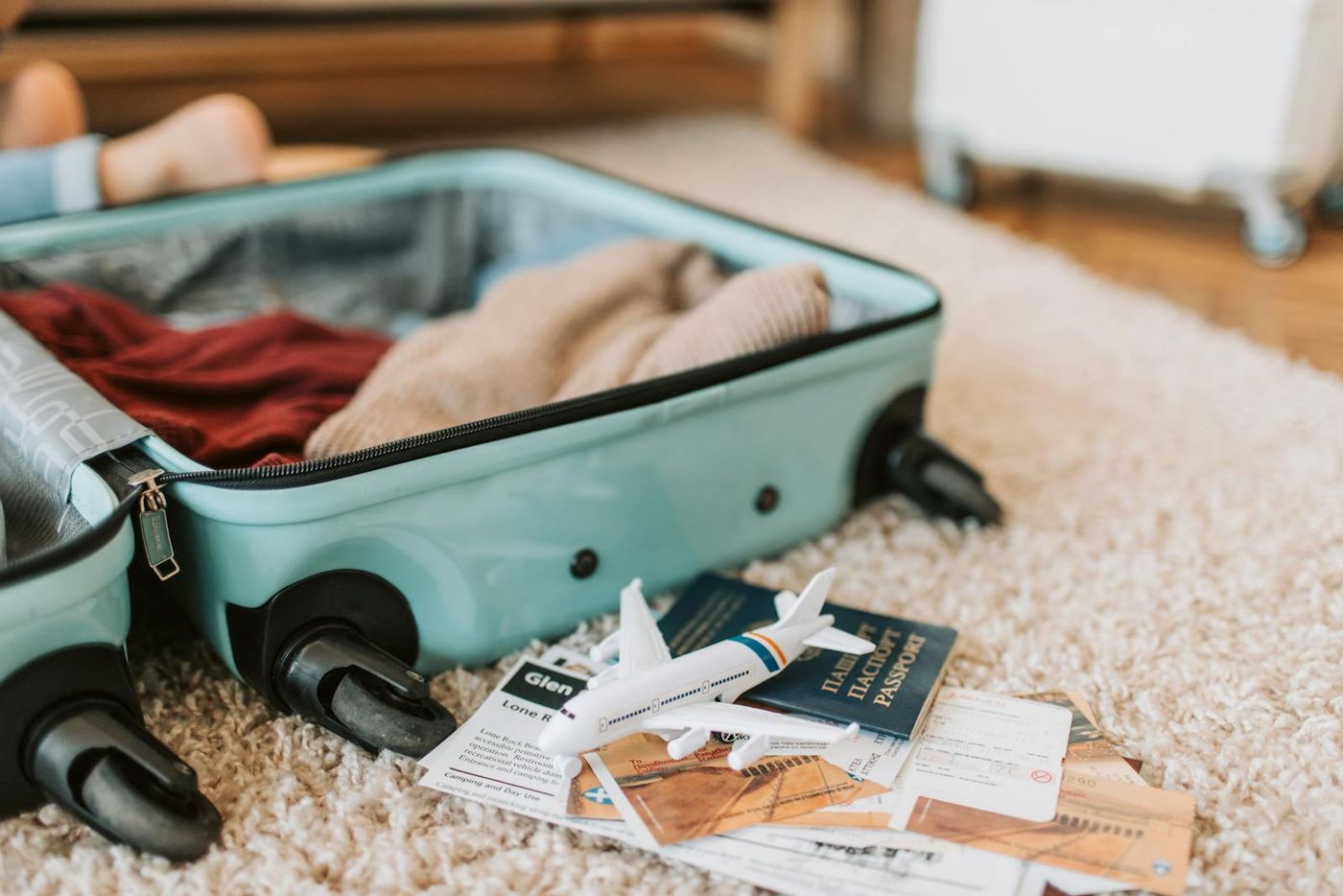 Open suitcase mid-packing with passport and tickets — pre-arrival visual (Pexels stock by Vlada Karpovich).